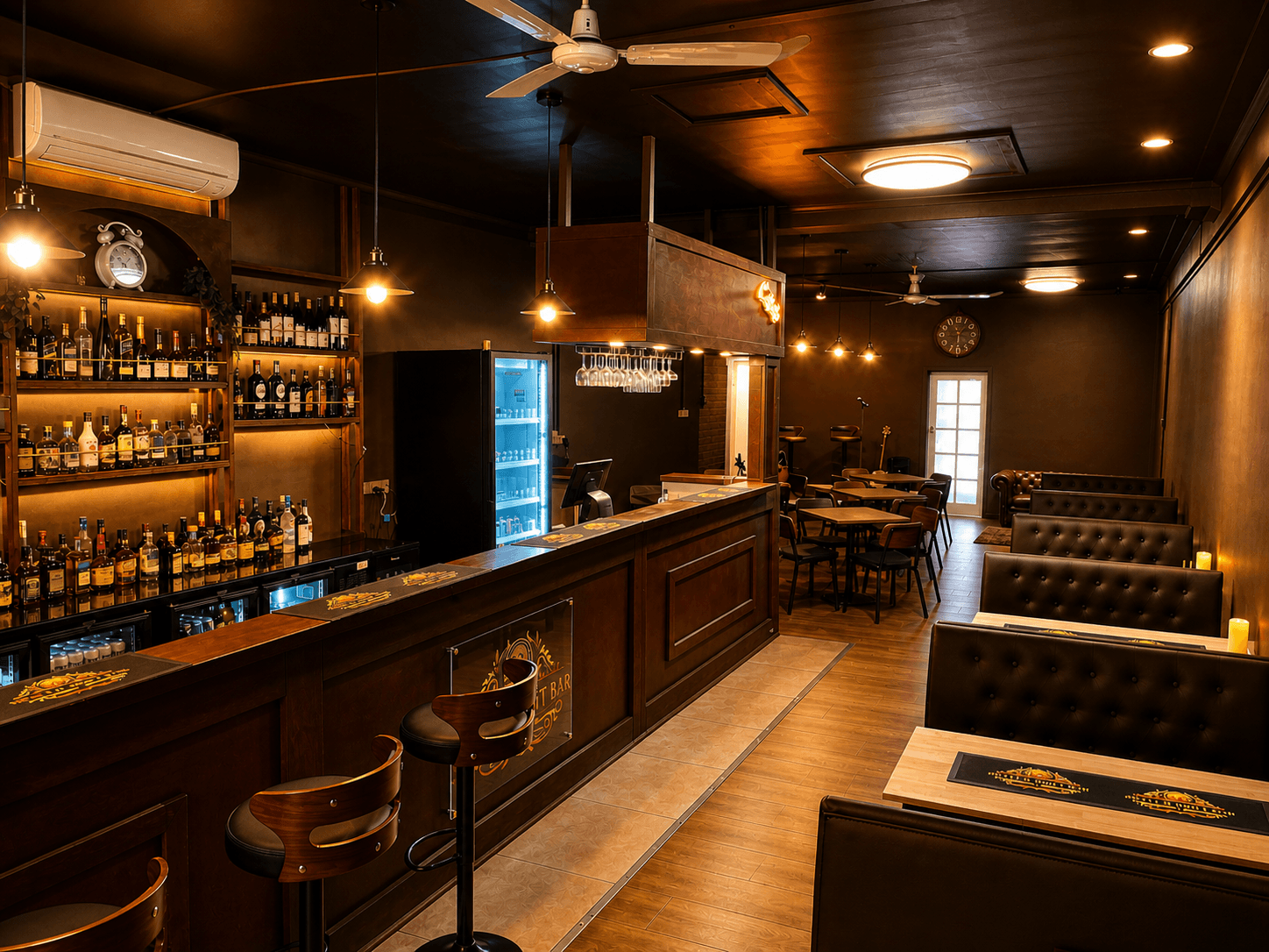 Dimly lit bar featuring a wooden counter, stocked liquor shelves, and black tufted leather booths.